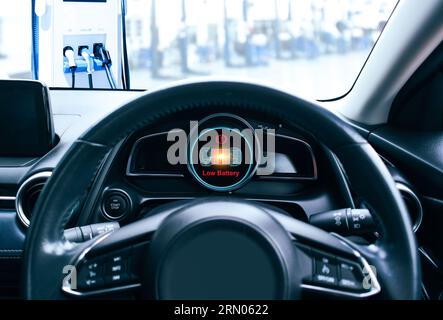Sullo schermo del quadro strumenti di un'auto elettrica viene visualizzato il messaggio di avvertenza batteria scarica, il segnale di tensione della batteria sta diminuendo e si sta scaricando. Foto Stock