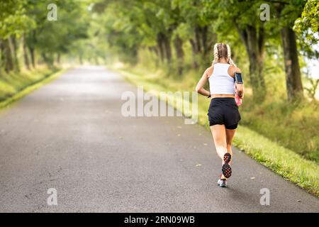 Vista posteriore di un corso di atletica femminile in natura. Foto Stock