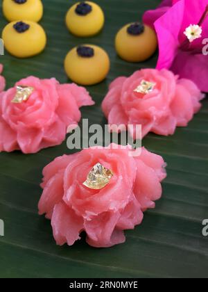 Snack dolci tailandesi di vario tipo e colore su foglia di banana con motivo intrecciato in ottone e metallo, ambientazione come tè pomeridiano o tè pomeridiano Foto Stock