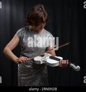 Ritratto a metà lunghezza di una donna che suona il violino su sfondo nero Foto Stock