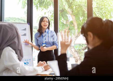 Una donna d'affari asiatica sicura e professionale o un'assistente di marketing donna ha permesso a tutti i partecipanti alla riunione di farle domande dopo aver terminato le sue relazioni pubbliche Foto Stock