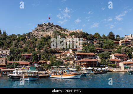 Villaggio e castello di Simena visti da un'imbarcazione turistica in arrivo, Simena, Kalekoy, Turchia Foto Stock