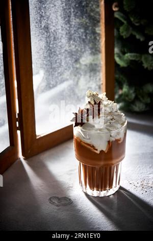 Bicchiere di cioccolata calda con panna montata. Neve in polvere di zucchero. Accogliente fotografia invernale. Foto Stock