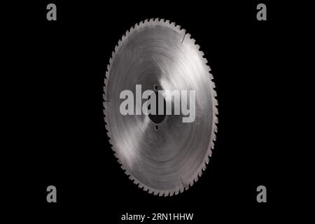 Lama per sega circolare in acciaio massiccia isolata su sfondo nero. Parte di macchine industriali con spazio di copia Foto Stock