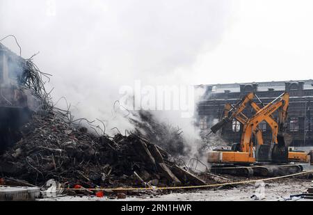 (150104) -- HARBIN, 4 gennaio 2015 -- macchinari pesanti rimuovono i detriti di un magazzino bruciato presso il mercato della ceramica Beifangnanxun nel distretto di Daowai, Harbin, capitale della provincia di Heilongjiang nella Cina nordorientale, 4 gennaio 2014. Il magazzino di Harbin City, che ha ucciso 5 vigili del fuoco, non è ancora stato completamente spento, hanno detto i vigili del fuoco locali domenica. Alle 10:40 di domenica, un edificio residenziale vicino al magazzino stava ancora morendo. I soccorritori hanno detto che la fonte dell'incendio è stata difficile da determinare a causa della complessa struttura dell'edificio, e l'edificio è a rischio di co Foto Stock