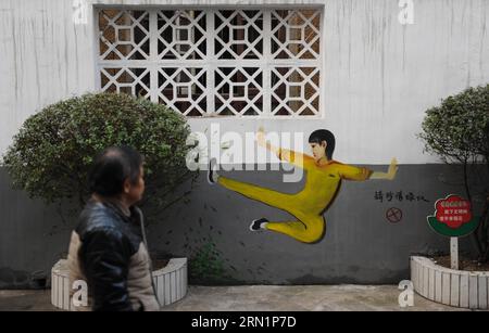 (150115) -- CHANGSHA, 15 gennaio 2015 -- Un uomo cammina davanti a un murale a cartoni animati che raffigura un praticante di arti marziali in un vestito di Bruce Lee in una comunità residenziale di Changsha, capitale della provincia di Hunan della Cina centrale, 15 gennaio 2015. Le pareti esterne di una comunità residenziale a Changsha sono state ringiovanite, dopo che un gruppo di giovani vignettisti sono stati invitati a creare circa 40 murales su di loro. I pittori murali non solo attingevano a muri semplici, ma mescolavano anche il loro lavoro con l'ambiente integrando oggetti sulla scena (scatole di giornali, casse di contatori di elettricità, aria condizionata u Foto Stock