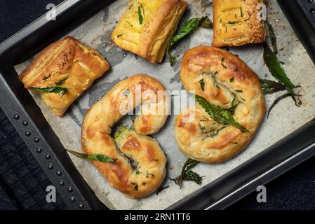 Cibo con cannabis. Torta fatta in casa, decorata con foglie di marijuana verde in un piatto da forno su marmo nero Foto Stock