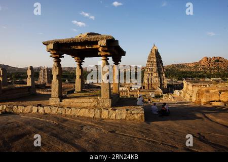 I turisti visitano il Tempio di Virupaksha e i suoi edifici circostanti a Hampi, nello stato del Karnataka, nel distretto Bellary dell'India, 6 febbraio 2015. Soprannominato Hampi: Il mondo perduto , l'austero e grandioso sito di Hampi fu l'ultima capitale dell'ultimo grande regno indù di Vijayanagar. I suoi principi favolosamente ricchi costruirono templi e palazzi dravidici che conquistarono l'ammirazione dei viaggiatori tra il XIV e il XVI secolo. Conquistata dalla confederazione musulmana del Deccan nel 1565, la città fu saccheggiata per un periodo di sei mesi prima di essere abbandonata. I gruppi di monumenti di Hampi furono arruolati come t Foto Stock