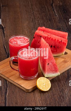 Freshly squeezed juice of ripe watermelon and pieces of watermelon. Wooden background, copy space. Stock Photo