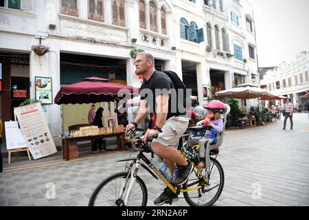 (150220) -- HAIKOU, 20 febbraio 2015 -- Uno straniero con i suoi bambini cicli per un tour sulla vecchia strada di Qilou ad Haikou, capitale della provincia di Hainan della Cina meridionale, 20 febbraio 2015. La vecchia strada Qilou, una famosa strada con una storia di più di un secolo, caratterizzata da edifici a più piani in stile sud-est asiatico che integrano stili architettonici cinesi ed europei, è stata elencata come una delle famose strade storiche cinesi. Molte persone vengono qui il terzo giorno del loro Festival di Primavera. ) (Wjq) CHINA-HAINAN-HAIKOU-SPRING FESTIVAL (CN) GuoxCheng PUBLICATIONxNOTxINxCHN Haikou 20 febbraio 2015 a straniero Foto Stock