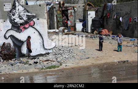 (150227) -- GAZA, 27 febbraio 2015 -- i bambini palestinesi giocano accanto a un murale di un gattino, dipinto dall'artista di strada britannico Banksy, sui resti di una casa distrutta durante l'offensiva israeliana di 50 giorni sulla Striscia di Gaza negli scorsi luglio e agosto, nella città settentrionale di Beit Hanun, nella Striscia di Gaza, il 27 febbraio 2015. MIDEAST-GAZA-MURALS-BANKSY YasserxQudih PUBLICATIONxNOTxINxCHN Gaza febbraio 27 2015 i bambini PALESTINESI giocano accanto a un murale di un gattino che quello che ha dipinto l'artista di strada britannico Banksy SUI resti di una Casa Thatcher che cosa ha distrutto durante gli attentati israeliani di 50 giorni Foto Stock