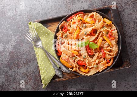 Reginette con peperoni e basilico in salsa di pomodoro cremosa con primi piani di capperi sul piatto sul tavolo. Vista superiore orizzontale dall'alto Foto Stock