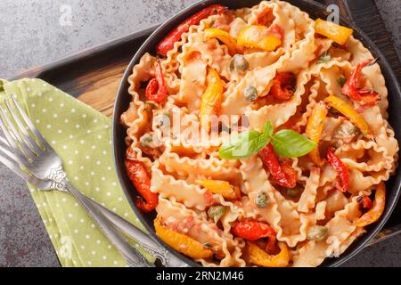 mafaldine con pasta italiana a forma di nastro, cucinata con salsa di pomodoro cremosa e peperoni da vicino in una ciotola sul tavolo. vista superiore orizzontale dall'alto Foto Stock
