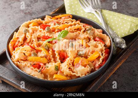 mafaldine con pasta italiana a forma di nastro, cucinata con salsa di pomodoro cremosa e peperoni da vicino in una ciotola sul tavolo. orizzontale Foto Stock