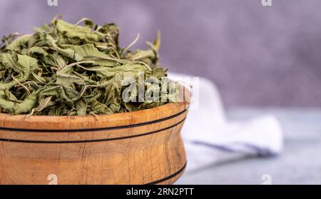 Tè di balsamo essiccato. Foglie di tè al balsamo al limone essiccate al sole in un recipiente di legno. erboristeria. Copia spazio Foto Stock