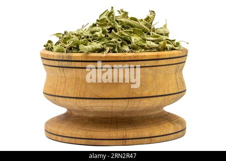 Foglie di tè Melissa. Foglie di tè di balsamo al limone essiccate al sole in una ciotola di legno isolata su sfondo bianco. erboristeria Foto Stock