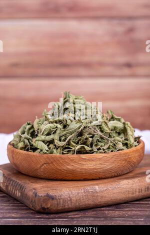 Tè di balsamo essiccato. Foglie di tè al balsamo al limone essiccate al sole in un recipiente di legno. erboristeria Foto Stock