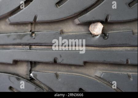 Chiodo arrugginito in acciaio negli pneumatici per auto macro primo piano. Tema pneumatico sgonfio Foto Stock