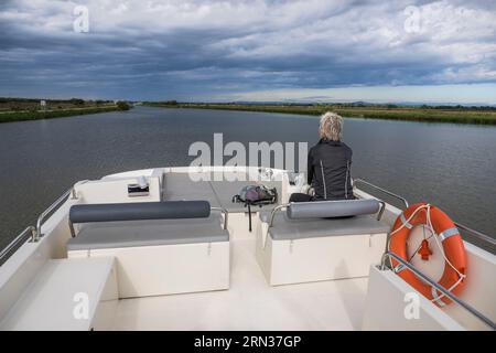 Francia, Gard, Aigues-Mortes, navigazione di una barca da diporto le Boat sul Rodano fino al Canale di Sète fuori città, Portes de Vidourle sullo sfondo Foto Stock