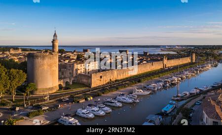 Francia, Gard, Aigues Mortes, la città medievale circondata dai suoi bastioni, la Torre di Costanza e il porto del Rodano al Canale di Sète in primo piano, le saline (Salins du Midi) sullo sfondo (vista aerea) Foto Stock