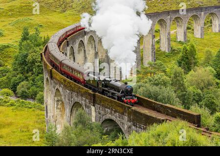 GLENFINNAN, SCOZIA - 16 AGOSTO 2023 - famoso allenamento a vapore che passa sopra un viadotto curvo a Glenfinnan nelle Highlands scozzesi Foto Stock