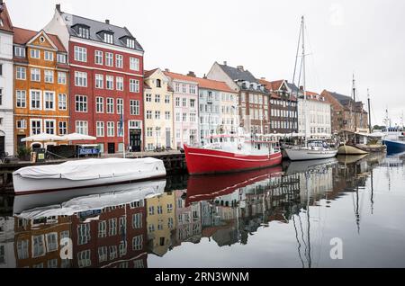 COPENAGHEN, Danimarca - Nyhavn, lo storico porto di Copenaghen, è visto animato da attività. Un tempo porto commerciale dove attraccavano navi da tutto il mondo, Nyhavn è ora un luogo di ritrovo culturale pieno di ristoranti, bar e case tradizionali, segnando la sua trasformazione da vivace centro marittimo a principale attrazione turistica. Foto Stock