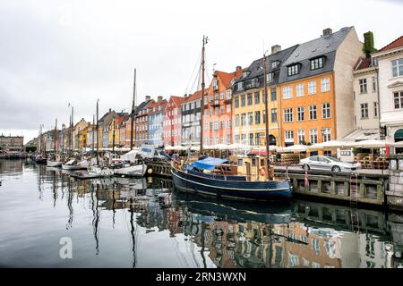 COPENAGHEN, Danimarca - Nyhavn, lo storico porto di Copenaghen, è visto animato da attività. Un tempo porto commerciale dove attraccavano navi da tutto il mondo, Nyhavn è ora un luogo di ritrovo culturale pieno di ristoranti, bar e case tradizionali, segnando la sua trasformazione da vivace centro marittimo a principale attrazione turistica. Foto Stock