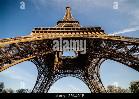 PARIGI, Francia - la Torre Eiffel si erge nel cielo, vista dalla sua base in una giornata di sole. L'iconica struttura a reticolo in ferro battuto, simbolo di Parigi, si estende verso l'alto, mostrando il suo complesso design architettonico. Foto Stock