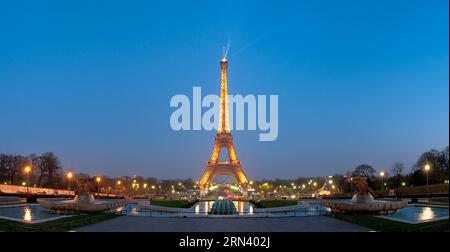 PARIGI, Francia - la Torre Eiffel si staglia contro un cielo crepuscolo nella capitale francese, Parigi. L'iconica struttura a reticolo di ferro è illuminata e le sue luci iniziano a brillare mentre il giorno sbiadisce nella notte sopra la città della luce. Foto Stock