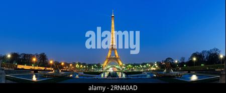 PARIGI, Francia - la Torre Eiffel si staglia contro un cielo crepuscolo nella capitale francese, Parigi. L'iconica struttura a reticolo di ferro è illuminata e le sue luci iniziano a brillare mentre il giorno sbiadisce nella notte sopra la città della luce. Foto Stock