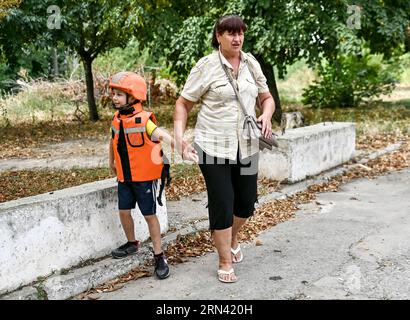 Non esclusiva: ZAPORIZHZHIA, UCRAINA - 31 AGOSTO 2023 - Una donna anziana tiene a mano un ragazzo in un casco e un giubbotto di salvataggio dopo che due famiglie sono state Foto Stock