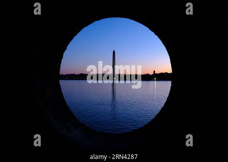 Monumento a Washington attraverso Stone Portal Tidal Basin Washington DC / WASHINGTON DC - il monumento a Washington è incorniciato drammaticamente attraverso un portale rotondo in pietra in un ponte presso il Tidal Basin, che si staglia contro i vibranti cieli pre-alba. L'obelisco di 555 piedi (169 metri), completato nel 1884, onora il primo presidente americano e si erge come la struttura in pietra più alta del mondo e l'obelisco più alto. Il bacino delle maree, un bacino artificiale parzialmente artificiale tra il fiume Potomac e il canale di Washington, fornisce uno dei punti panoramici più fotogenici della capitale per vedere il monumento. Foto Stock