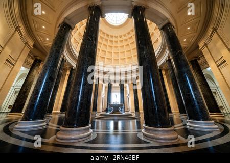 WASHINGTON, DC, Stati Uniti: La grande rotunda della National Gallery of Art di Washington, DC, mostra l'architettura neoclassica con la sua imponente cupola, il lucernario e le colonne corinzie. Una fontana centrale aggiunge un elemento dinamico allo spazio circolare, che funge da ingresso principale e punto focale del museo. Il design della rotonda, caratterizzato da un layout simmetrico e proporzioni classiche, esemplifica la visione dell'architetto John Russell Pope. Foto Stock