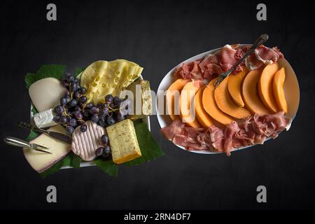 Piatti freddi a buffet con melone, prosciutto e formaggio su sfondo scuro, Baviera, Germania Foto Stock