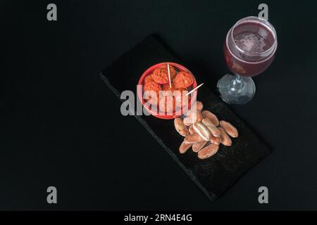 Chorizo iberico, salsiccia iberica, fritta in vaso di argilla con pane e vino rosso tipico tapa spagnolo isolato su fondo nero e spazio copia Foto Stock