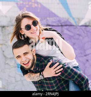 Bel giovane sorridente che prende il suo maialino cavalca la schiena Foto Stock