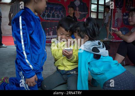 (150531) -- HEFEI, 31 maggio 2015 -- foto scattata il 26 maggio 2015 mostra i bambini che giocano su un cellulare dopo aver fatto esercizi acrobatici in una scuola di acrobazie nel villaggio di Sanwang, nella contea di Yingshang nella provincia di Anhui della Cina orientale. Fondata nel 2007, la scuola di acrobazie nel villaggio di Sanwang iscrive più di un centinaio di bambini ogni anno, che imparano acrobazie per guadagnarsi da vivere. ) (Zwx) CHINA-ANHUI-YINGSHANG-CHILDREN-ACROBATICS(CN) GuoxChen PUBLICATIONxNOTxINxCHN 150531 Hefei May 31 2015 la foto scattata IL 26 2015 maggio mostra i bambini che giocano ai giochi SU un cellulare dopo aver fatto esercizi acrobatici i Foto Stock