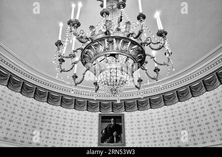 Lampadario e ritratto, Casa Bianca, Washington DC — Foto in bianco e nero | Lampadario e ritratto, Casa Bianca, Washington, D.C. Fotografia in bianco e nero da un angolo basso, che mostra il lampadario ornato sospeso sopra un ritratto sul muro. Foto Stock