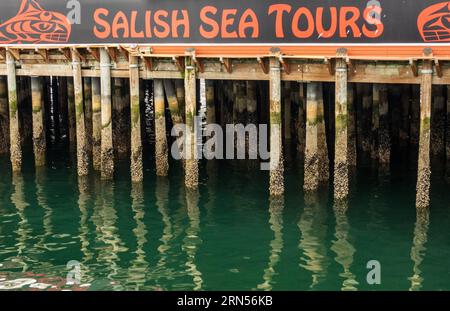 Seattle, WA - 5 agosto 2023: Cartello Salish Sea Tours sul vecchio molo di barnacle 57 pilastri in legno Foto Stock