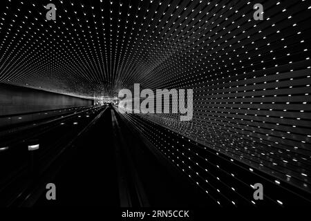 Tunnel leggero, City. Fotografia in bianco e nero che mostra linee parallele di luci che convergono in distanza. Foto Stock