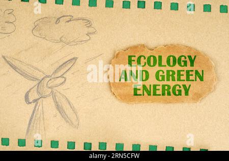 A wind generator and clouds are drawn on cardboard with green holes, next to it lies a cardboard with the inscription - Ecology And Green Energy. Ecol Stock Photo