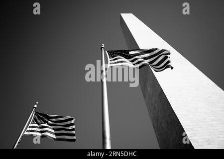 Monumento di Washington con bandiere, Washington DC — Foto in bianco e nero | Monumento di Washington con bandiere, Washington, D.C. Fotografia in bianco e nero che mostra il monumento da un angolo basso, con due bandiere americane in primo piano. Foto Stock