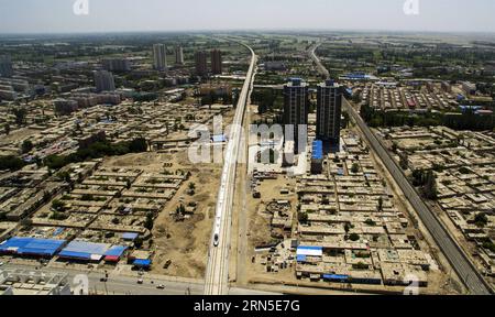 (150623) -- URUMQI, 23 giugno 2015 -- foto scattata con un drone il 21 maggio 2015 mostra un treno proiettile che attraversa la città di Hami, nella regione autonoma di Xinjiang Uygur della Cina nord-occidentale. La ferrovia ad alta velocità di Lanxin, lunga 1.776 chilometri, fu messa in funzione il 26 dicembre 2014, collegando Lanzhou, capitale della provincia di Gansu, Xining, capitale della provincia di Qinghai, e Urumqi, tutte nel nord-ovest della Cina. Nel 2015, foto aeree della sezione Xinjiang della ferrovia ad alta velocità di Lanxin sono state scattate da un gruppo di fotografia aerea dell'Agenzia di notizie Xinhua e varie forme di terra dello Xinjiang sono state registrate. P) CHINA-LANXIN HIG Foto Stock