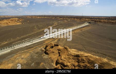 (150623) -- URUMQI, 23 giugno 2015 -- la foto scattata con un drone il 9 giugno 2015 mostra un treno proiettile che attraversa l'area di Yadan a Turpan, nella regione autonoma di Xinjiang Uygur della Cina nord-occidentale. La ferrovia ad alta velocità di Lanxin, lunga 1.776 chilometri, fu messa in funzione il 26 dicembre 2014, collegando Lanzhou, capitale della provincia di Gansu, Xining, capitale della provincia di Qinghai, e Urumqi, tutte nel nord-ovest della Cina. Nel 2015, foto aeree della sezione Xinjiang della ferrovia ad alta velocità di Lanxin sono state scattate da un gruppo di fotografia aerea dell'Agenzia di notizie Xinhua e varie forme di terra dello Xinjiang sono state registrate. (p) Foto Stock