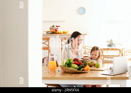 Bambina con sua madre che sbuccia la mela in cucina Foto Stock