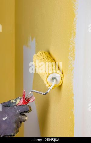 La parete è verniciata con vernice gialla, a mano con rullo per pittura Foto Stock