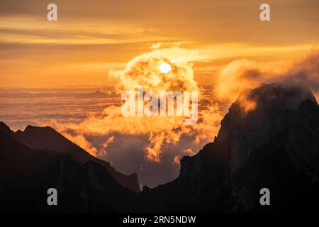 Alba, sole che splende sulle montagne nella nebbia, Saentis, Appenzell Ausserrhoden, Appenzell Alps, Svizzera Foto Stock