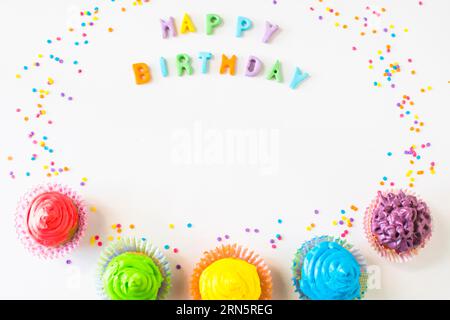 Buon compleanno testo con muffin colorati sfondo bianco Foto Stock