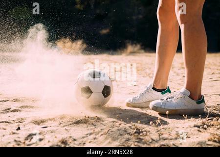 Coltiva le gambe atletiche in piedi accanto al calcio all'aperto Foto Stock