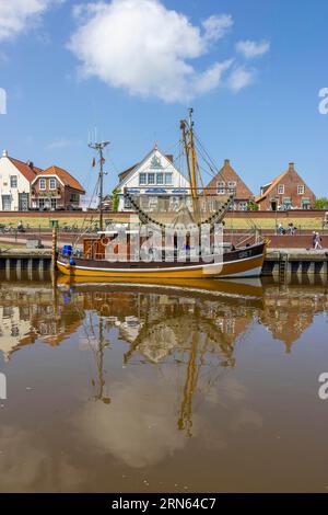 Taglia granchio con riflesso nell'acqua nel porto di Greetsiel con case storiche, Greetsiel, Frisia orientale, Mare del Nord, bassa Sassonia, Germania Foto Stock